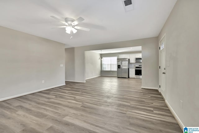 unfurnished living room with wood finished floors, visible vents, baseboards, and ceiling fan