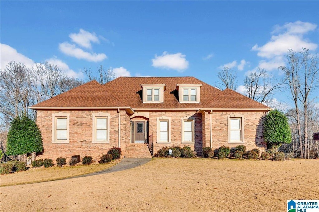 view of front of house with brick siding and roof with shingles