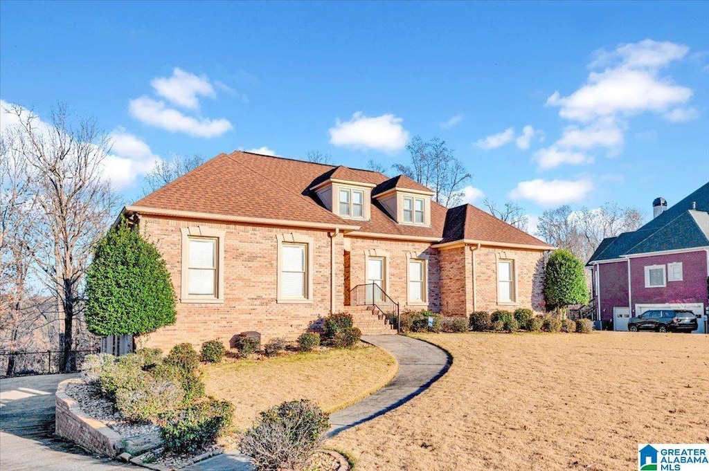 view of front facade with brick siding and a shingled roof