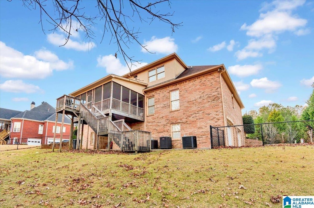 back of house with a sunroom, fence, stairway, brick siding, and a yard