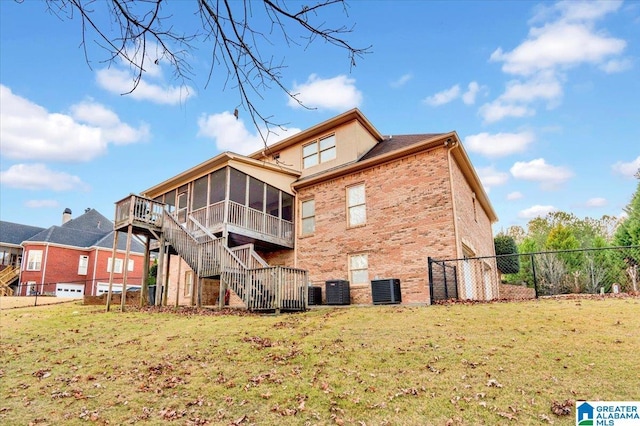 back of house with a sunroom, fence, stairway, brick siding, and a yard