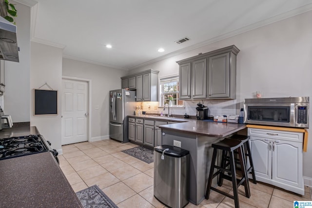 471 River Oaks Ln, Helena, AL 35080 - kitchen featuring appliances with stainless steel finishes, gray cabinets, a peninsula, light tile patterned flooring, and ornamental molding