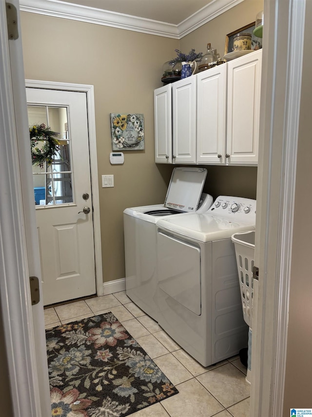 clothes washing area with crown molding, baseboards, washer and dryer, cabinet space, and light tile patterned floors
