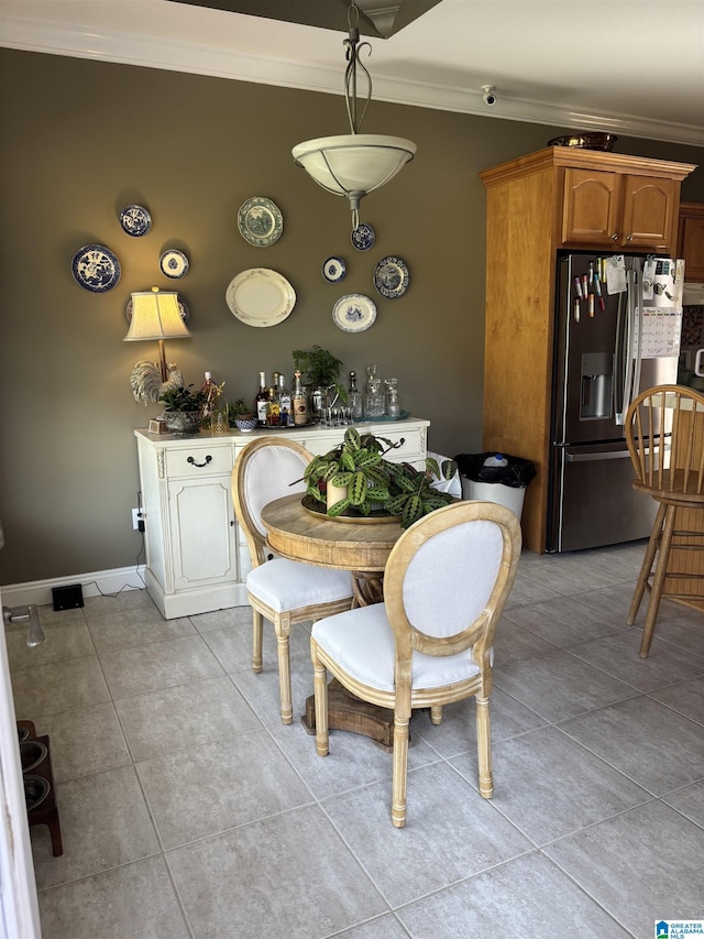 dining space with light tile patterned floors, ornamental molding, and baseboards