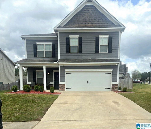 craftsman house featuring a front lawn, fence, stone siding, and driveway