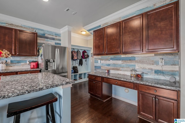 kitchen with crown molding, visible vents, stainless steel refrigerator with ice dispenser, light stone counters, and built in study area