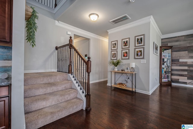 stairs with crown molding, wood finished floors, baseboards, and visible vents
