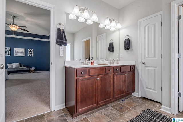 full bath with a sink, double vanity, baseboards, and a ceiling fan