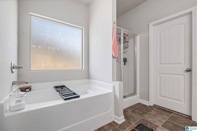 bathroom featuring a stall shower, a garden tub, and baseboards