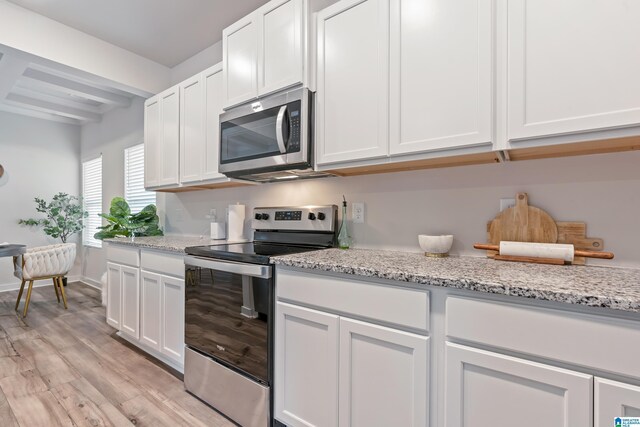 kitchen with white cabinetry, light stone countertops, appliances with stainless steel finishes, and light wood-type flooring