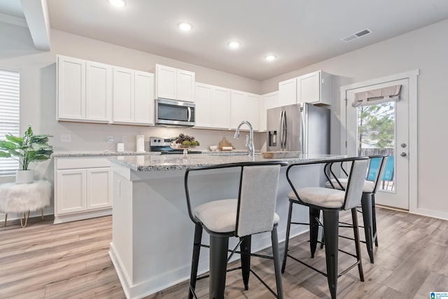 kitchen featuring light wood-type flooring, white cabinets, appliances with stainless steel finishes, and visible vents