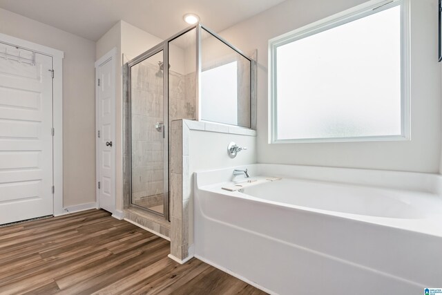 bathroom with wood finished floors, a garden tub, and a shower stall