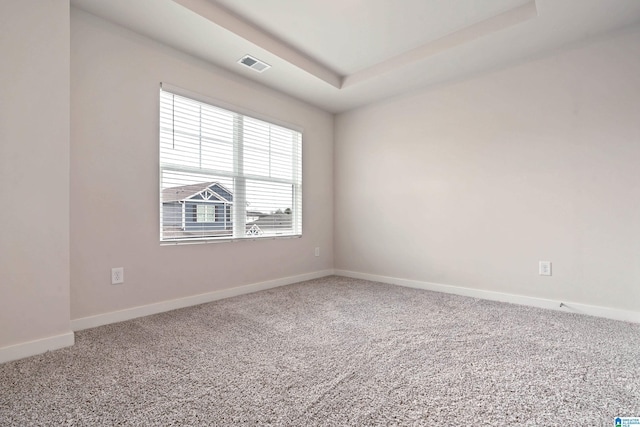 unfurnished room featuring a tray ceiling, baseboards, visible vents, and carpet flooring