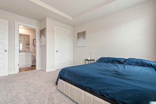 bedroom with carpet flooring, ensuite bath, and baseboards