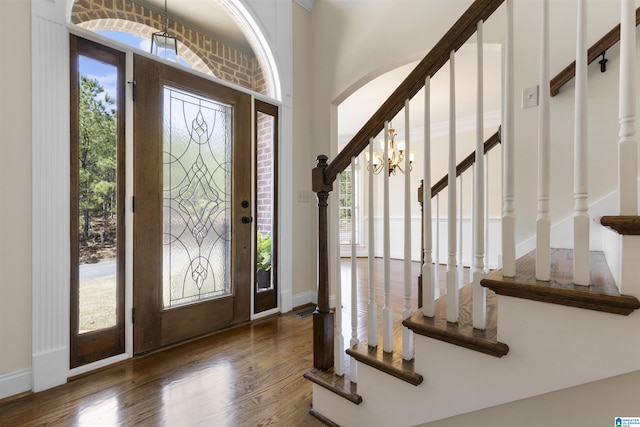 entryway featuring stairs, arched walkways, wood finished floors, and baseboards