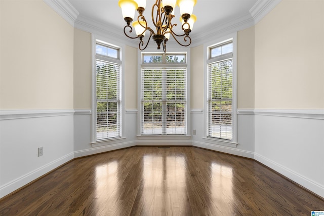 unfurnished dining area with an inviting chandelier, a wealth of natural light, crown molding, and wood finished floors