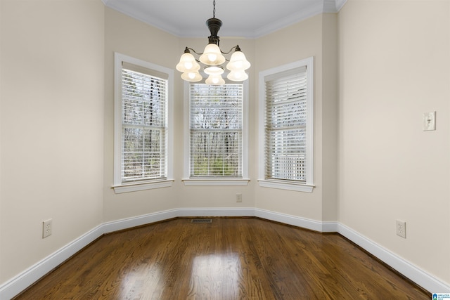 unfurnished dining area featuring dark wood-type flooring, baseboards, ornamental molding, and an inviting chandelier