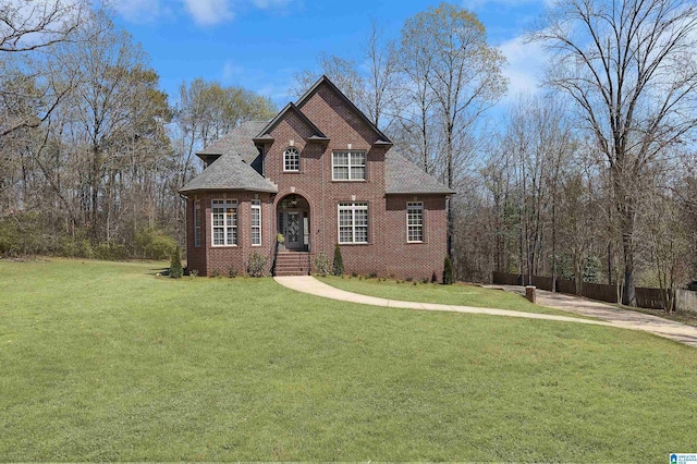 view of front facade with a front lawn, fence, brick siding, and roof with shingles