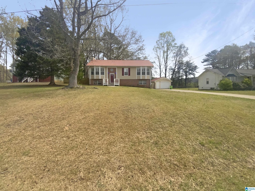split foyer home featuring an outbuilding, metal roof, a detached garage, entry steps, and a front lawn