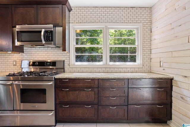 5605 7th Ave S, Birmingham, AL 35212 - kitchen with wood walls, dark brown cabinets, stainless steel appliances, and light stone countertops
