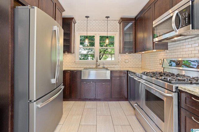 5605 7th Ave S, Birmingham, AL 35212 - kitchen with stainless steel appliances, a sink, light stone countertops, decorative backsplash, and glass insert cabinets