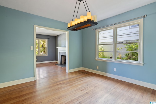 5605 7th Ave S, Birmingham, AL 35212 - unfurnished living room featuring a fireplace with flush hearth, baseboards, a chandelier, and wood finished floors