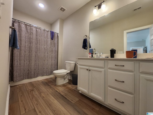 full bathroom featuring wood-type flooring, toilet, vanity, and visible vents