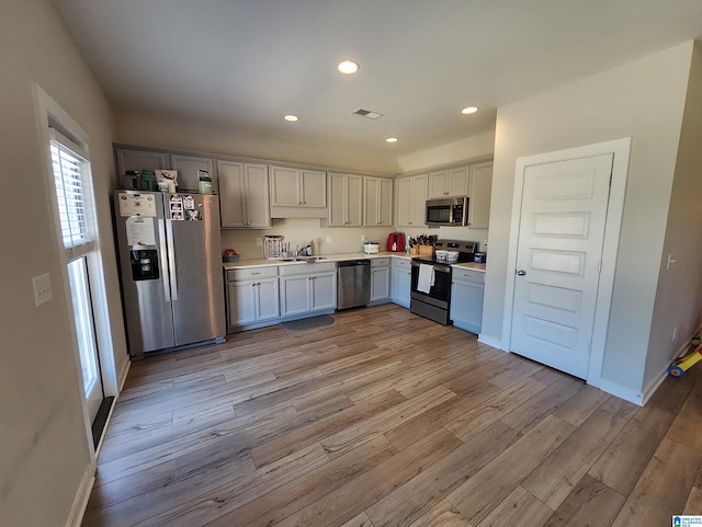 kitchen featuring light wood-style flooring, a sink, light countertops, and stainless steel appliances