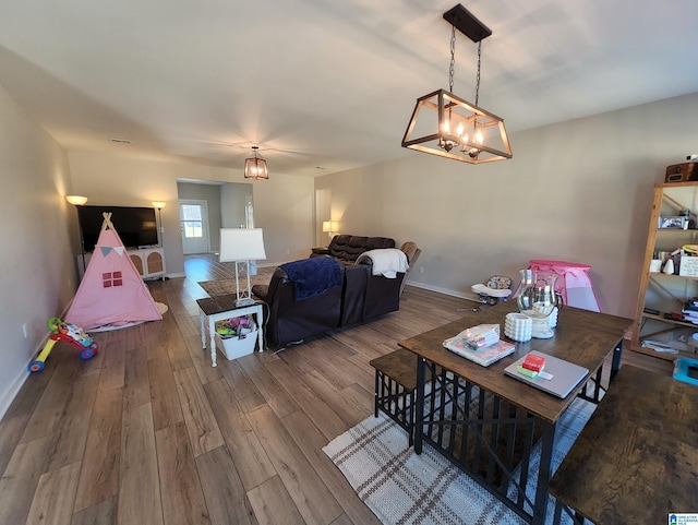 living area with a chandelier, baseboards, and wood finished floors