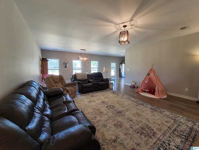 living area featuring wood finished floors, visible vents, baseboards, and plenty of natural light