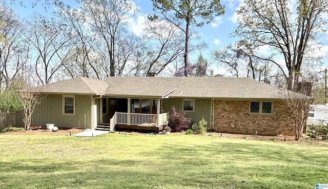 back of property featuring a lawn, a chimney, fence, and brick siding