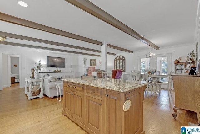 kitchen featuring light wood-type flooring, a center island, a chandelier, beamed ceiling, and light stone countertops