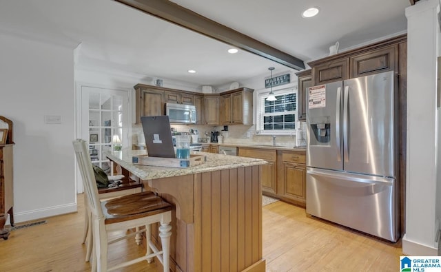 kitchen with a kitchen island, tasteful backsplash, appliances with stainless steel finishes, visible vents, and light wood-style floors