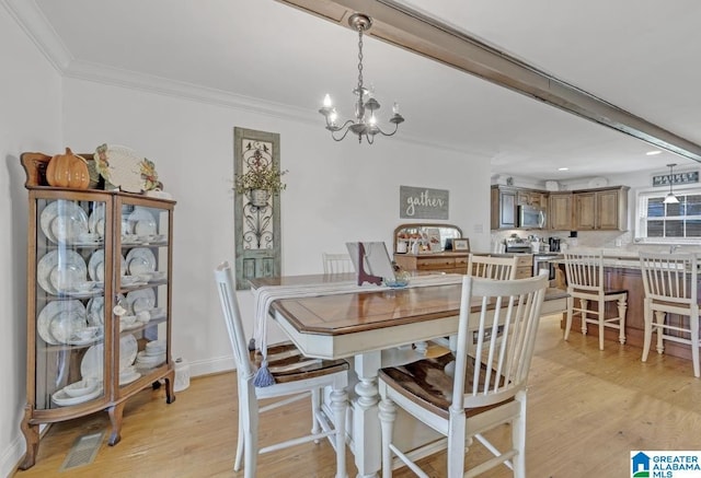 dining area featuring baseboards, ornamental molding, an inviting chandelier, and light wood-style floors
