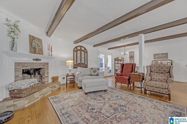 living room featuring an inviting chandelier, a fireplace with raised hearth, baseboards, beamed ceiling, and wood finished floors