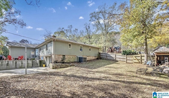 view of side of home with fence, an attached garage, central AC unit, brick siding, and a chimney