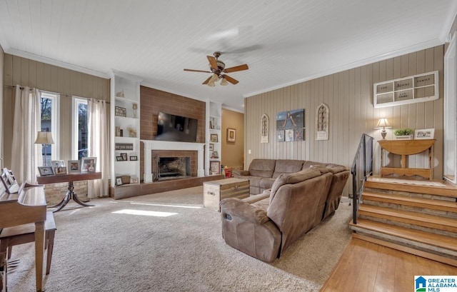 living area with a ceiling fan, crown molding, and a fireplace with raised hearth