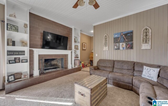 living room featuring a large fireplace, crown molding, carpet, and a ceiling fan