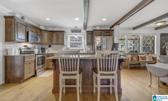 kitchen with beam ceiling, appliances with stainless steel finishes, backsplash, and a wealth of natural light