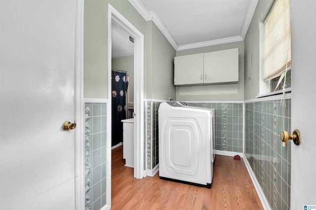 washroom with tile walls, light wood-style flooring, washer / clothes dryer, ornamental molding, and cabinet space
