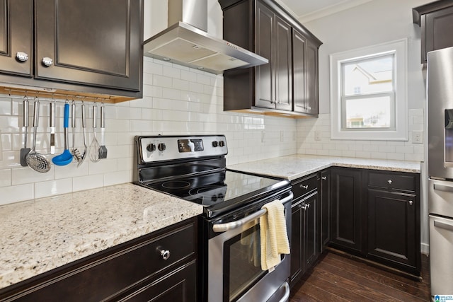 kitchen featuring tasteful backsplash, wall chimney exhaust hood, dark wood finished floors, stainless steel appliances, and light stone counters