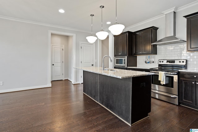 kitchen with wall chimney exhaust hood, ornamental molding, appliances with stainless steel finishes, a sink, and a center island with sink