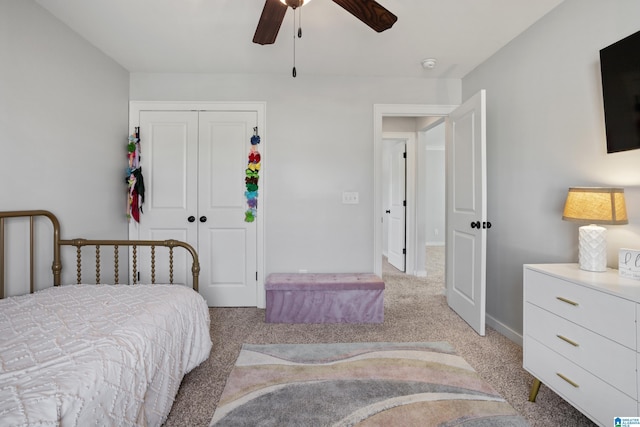 bedroom featuring a closet, light colored carpet, baseboards, and a ceiling fan