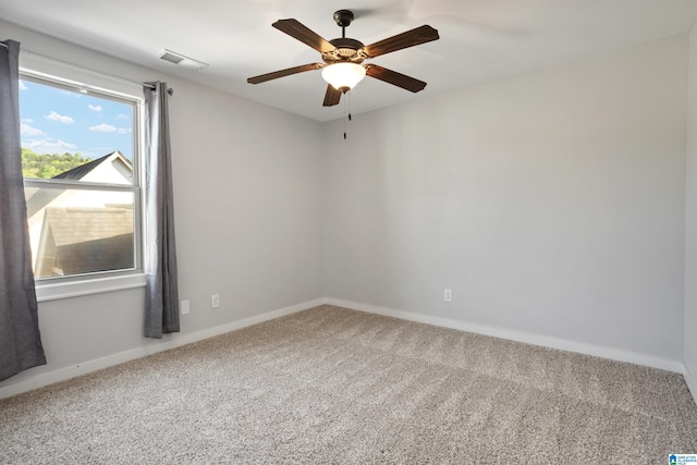 carpeted empty room with visible vents, baseboards, and a ceiling fan