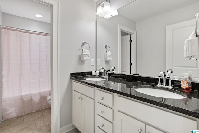 full bathroom featuring toilet, double vanity, a sink, and a shower with curtain