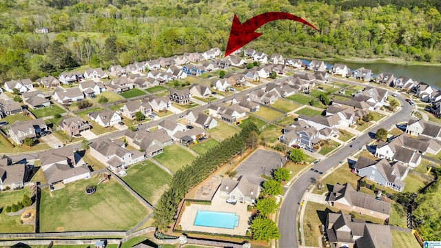 drone / aerial view featuring a wooded view, a residential view, and a water view