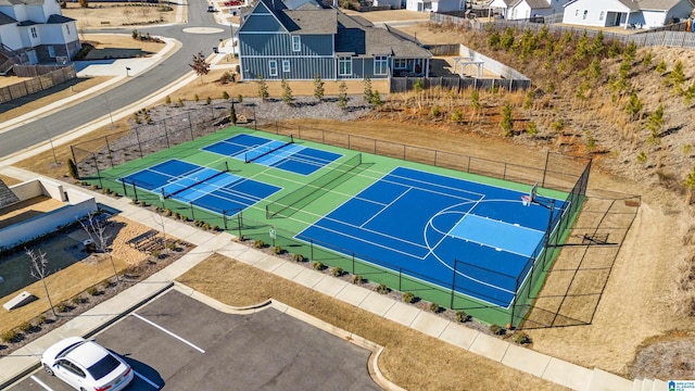 view of basketball court featuring a tennis court, fence, and a residential view