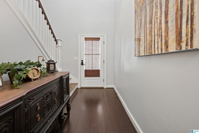 entryway featuring dark wood-type flooring, a high ceiling, baseboards, and stairs