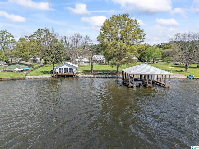 dock area with boat lift, a water view, and a lawn