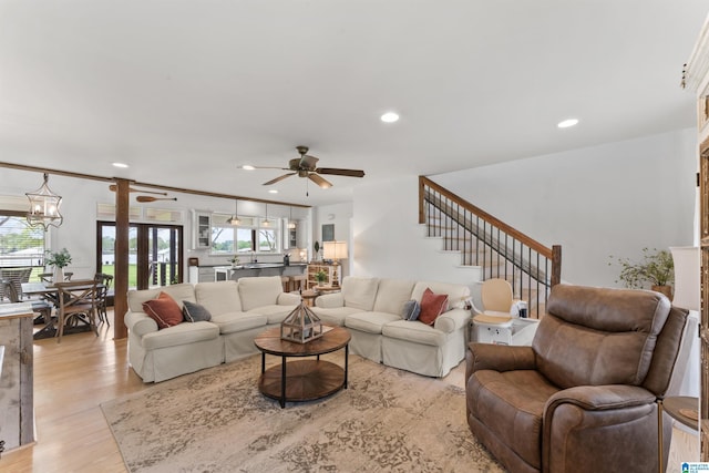 living area featuring light wood-style flooring, a healthy amount of sunlight, recessed lighting, and ceiling fan with notable chandelier
